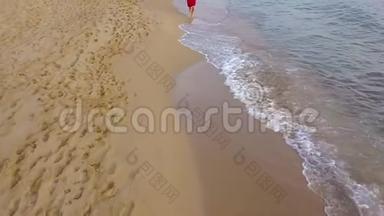 一个女人赤脚走在潮湿的沙滩上的俯视图。 海浪冲刷着沙滩上的脚印